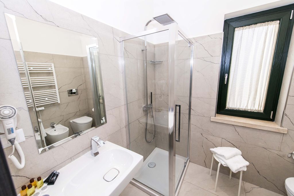 A modern bathroom with a glass-enclosed shower, a white sink, and a large mirror.
