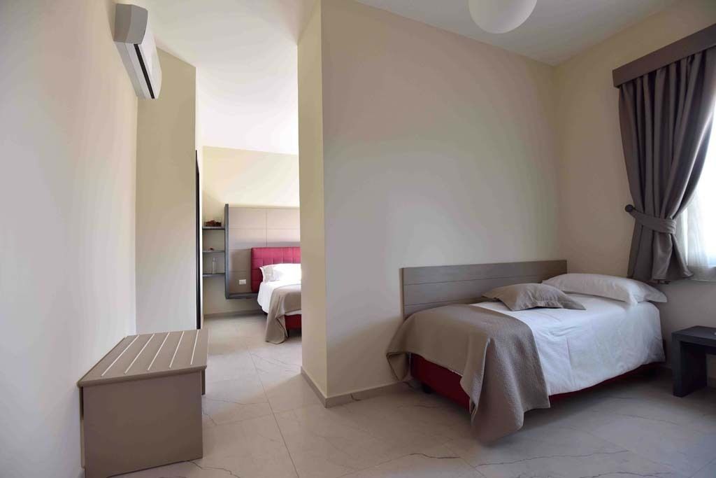 A modern hotel room with a large bed, a bedside table, and a small seating area.