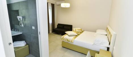 A modern hotel room with a large bed, a bedside table, a desk, and a shower area.