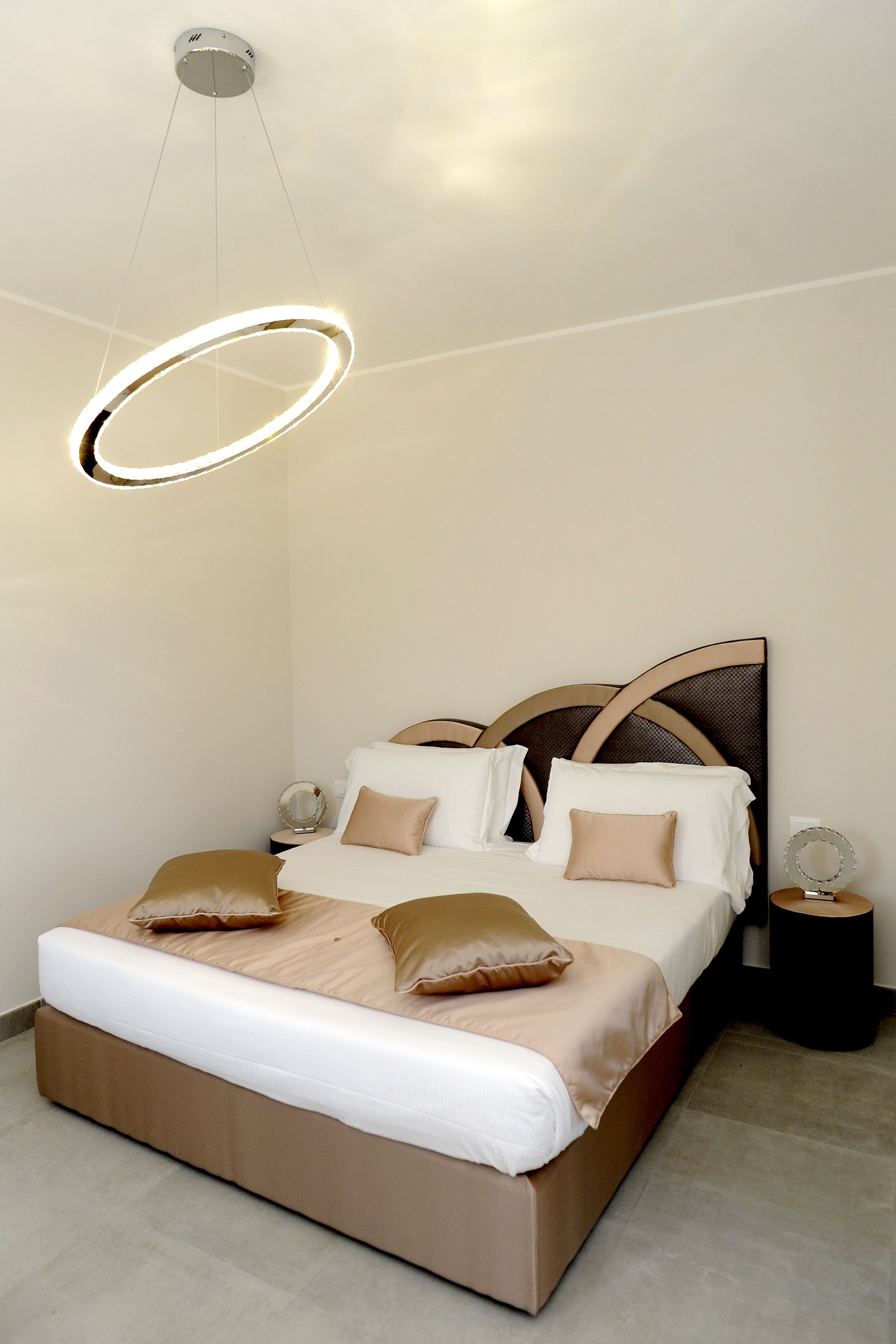 A modern bedroom with a large bed, a circular light fixture, and a wooden headboard.