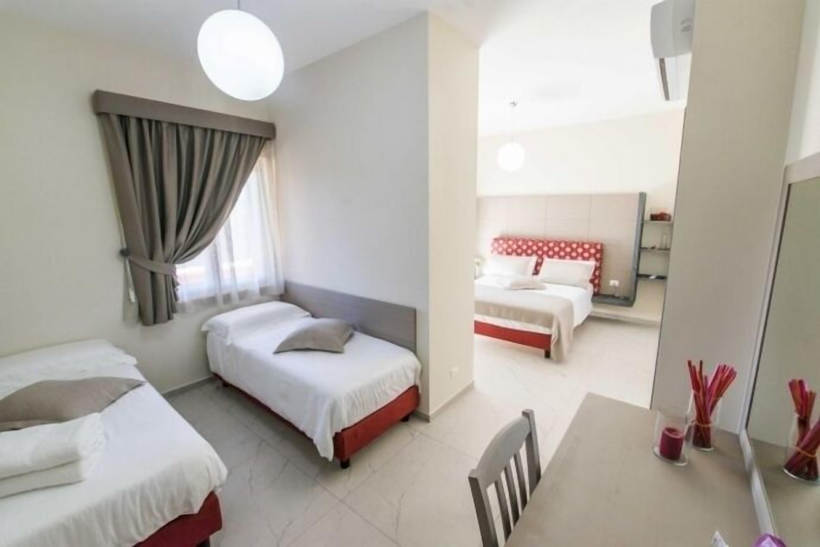 Quarto de hotel com duas camas, uma escrivaninha e um espelho.