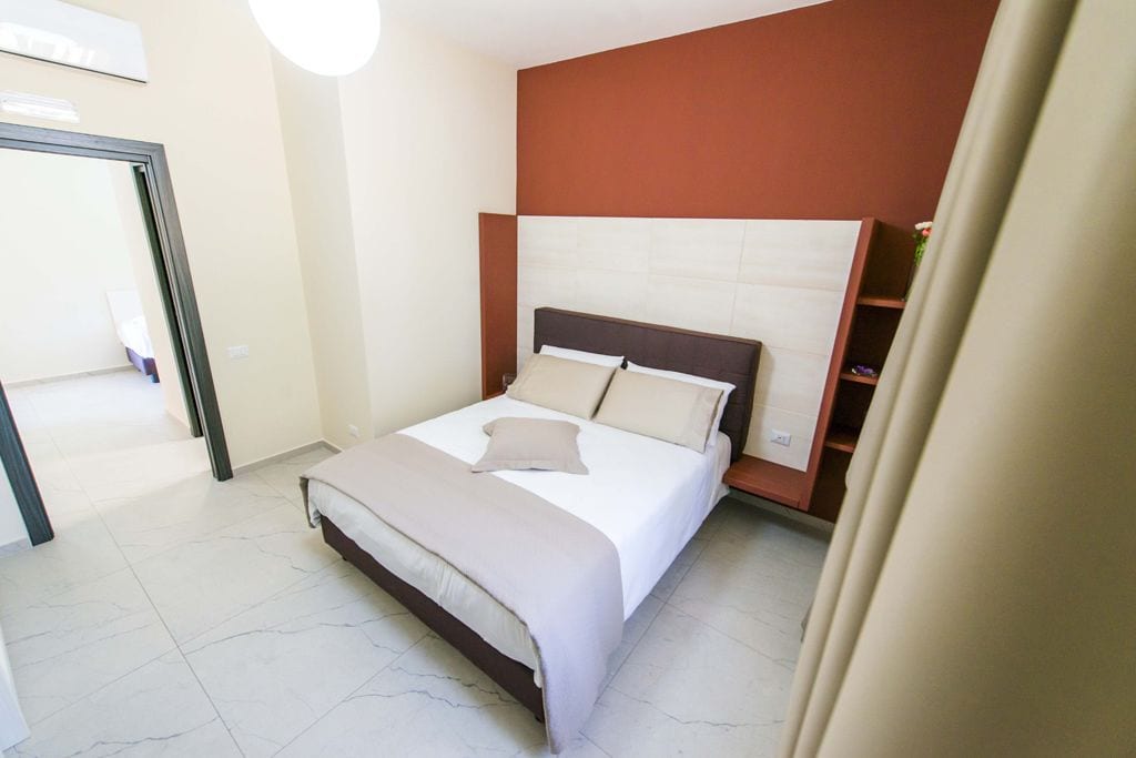 Un dormitorio con cama, cabecera y puerta.