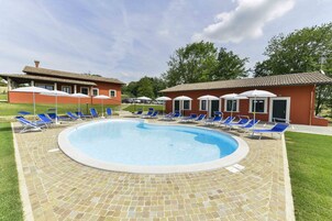 Una piscina al aire libre, sombrillas, sillones reclinables de piscina