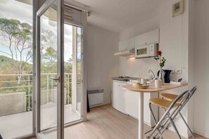 A modern kitchen with a microwave, a sink, and a small dining area with a chair. - City Résidence Sophia (Valbonne)