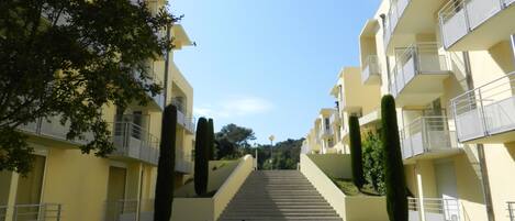 A pathway leading to a building with multiple balconies and a staircase.
