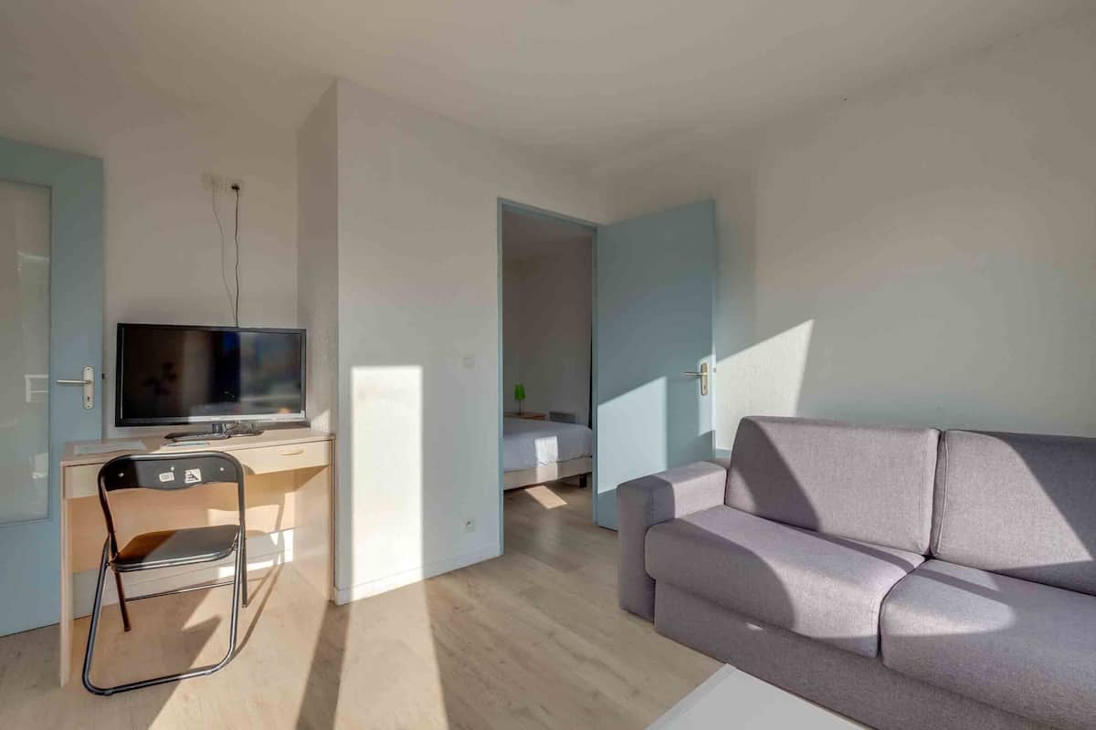 Ein modernes Wohnzimmer mit Flachbildfernseher, einer Couch und einem Schreibtisch mit Stuhl.