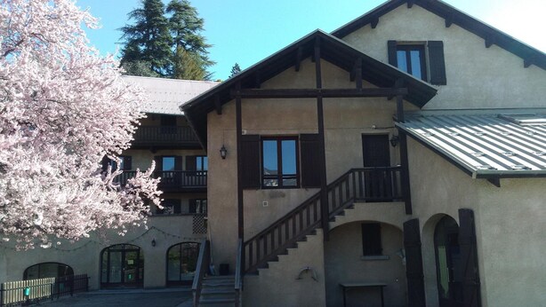 A two-story building with a staircase leading to the upper floor. There are multiple windows and balconies. - CapVerb (Guillestre)