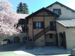 A two-story building with a staircase leading to the upper floor. There are multiple windows and balconies.