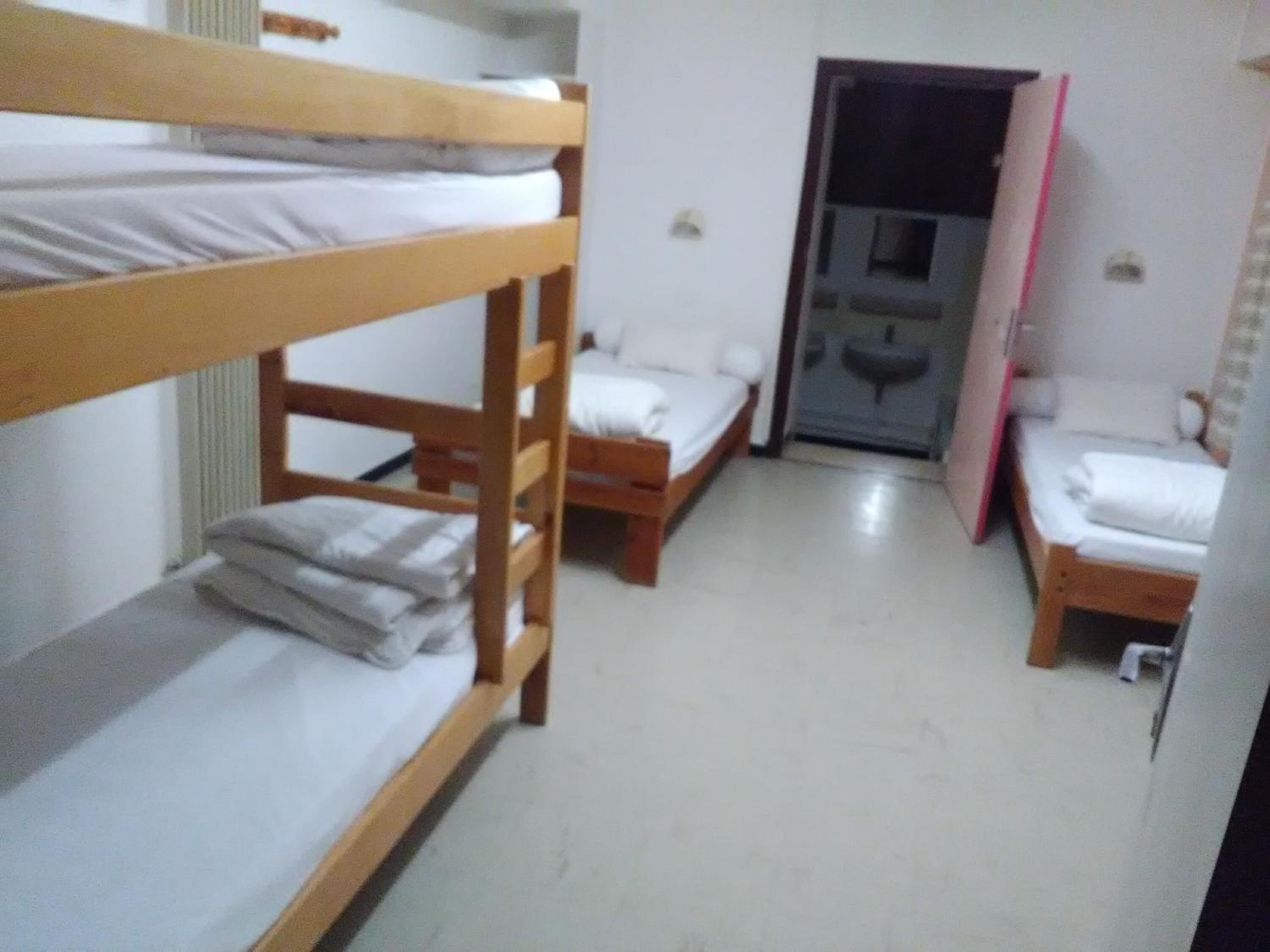 Un dormitorio con literas, una pequeña kitchenette y una puerta que da a otra habitación.
