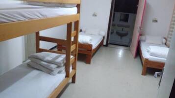 Un dormitorio con literas, una pequeña kitchenette y una puerta que da a otra habitación.