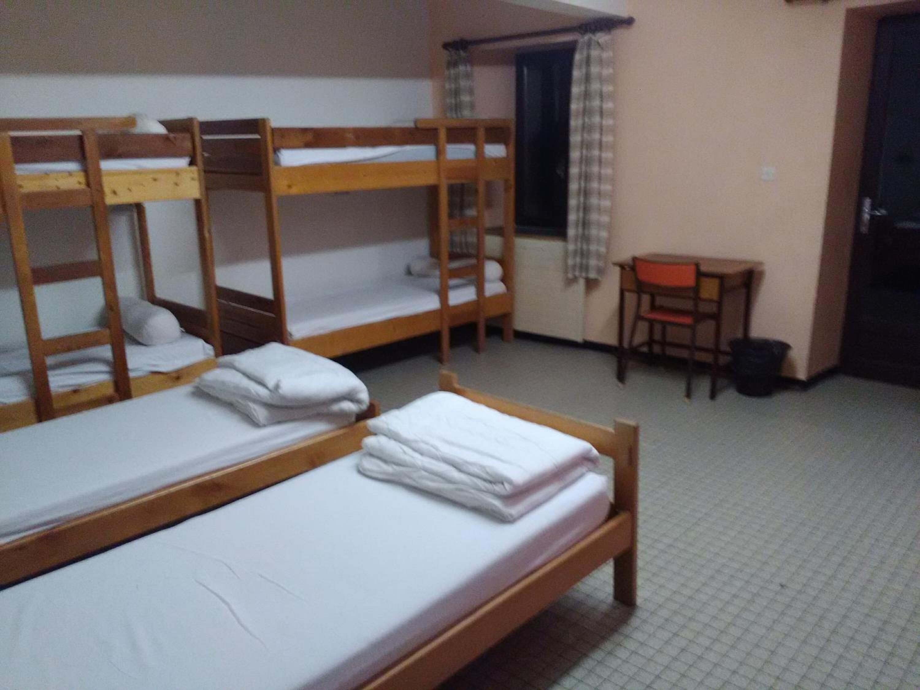 Un dormitorio con literas, un escritorio y una silla.