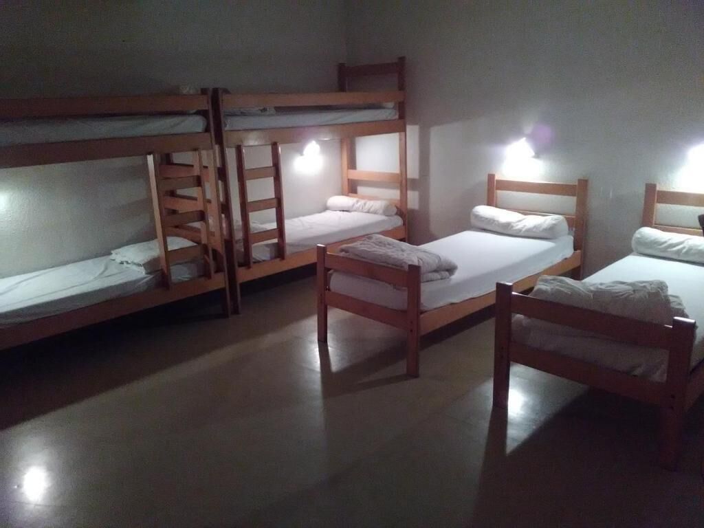 A dormitory room with bunk beds, a single bed, and a chair.