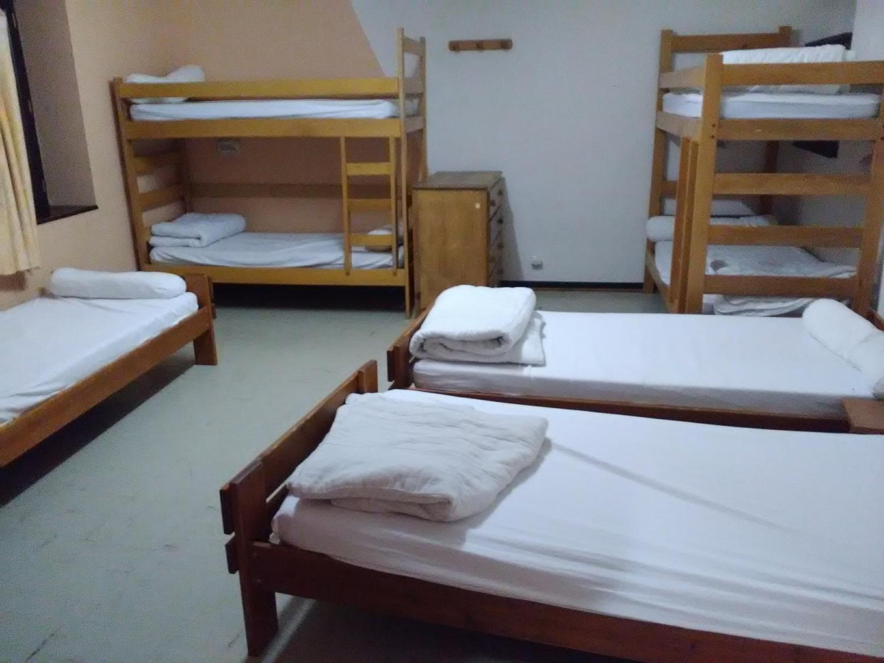Un dormitorio con literas, un escritorio pequeño y una puerta blanca.