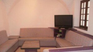 A compact living room with a sofa, a coffee table, and a television on a stand. - CapVerb (Guillestre)
