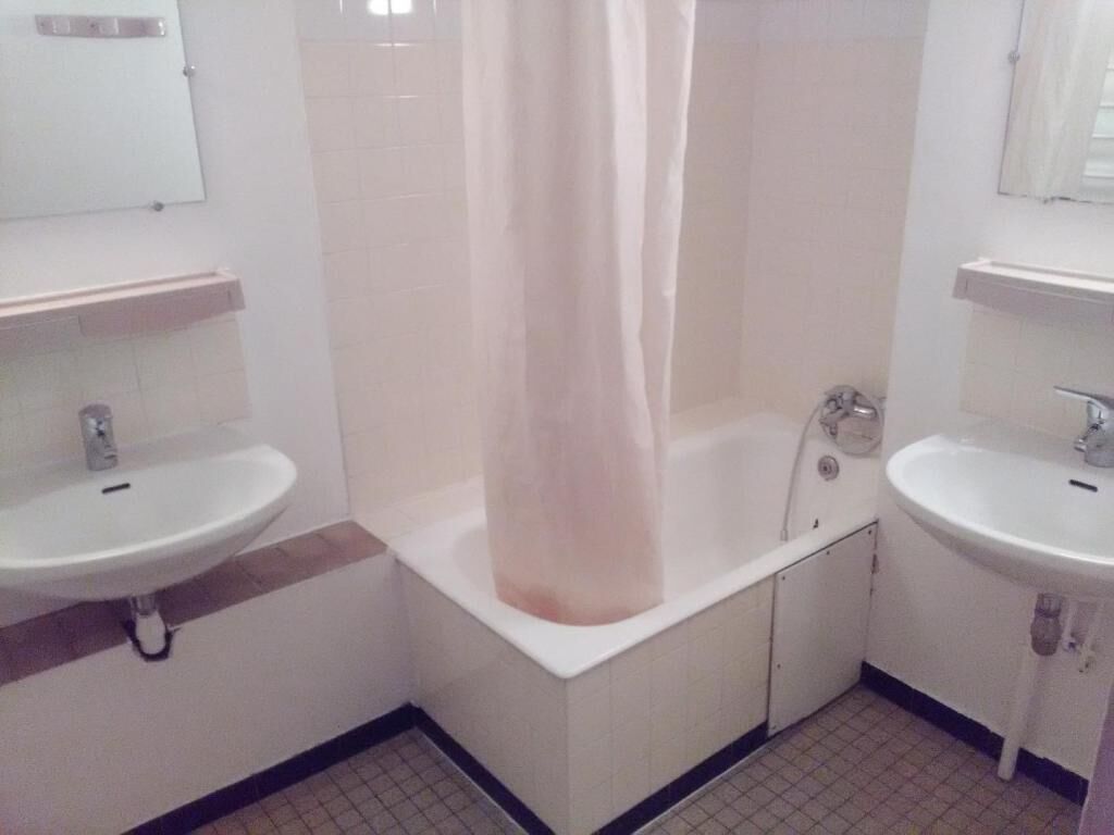 A bathroom with two sinks, a bathtub, and a shower curtain.