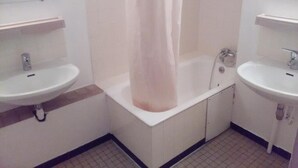 A bathroom with two sinks, a bathtub, and a shower curtain.