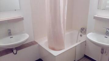 A bathroom with two sinks, a bathtub, and a shower curtain.