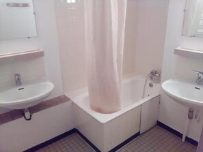 A bathroom with two sinks, a bathtub, and a shower curtain.