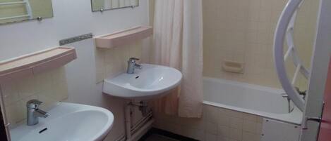 A bathroom with two sinks, a bathtub, a mirror, and a shower curtain.