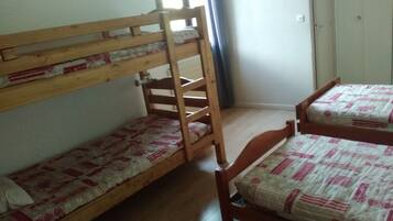 Een slaapzaal met stapelbedden en een houten stoel.