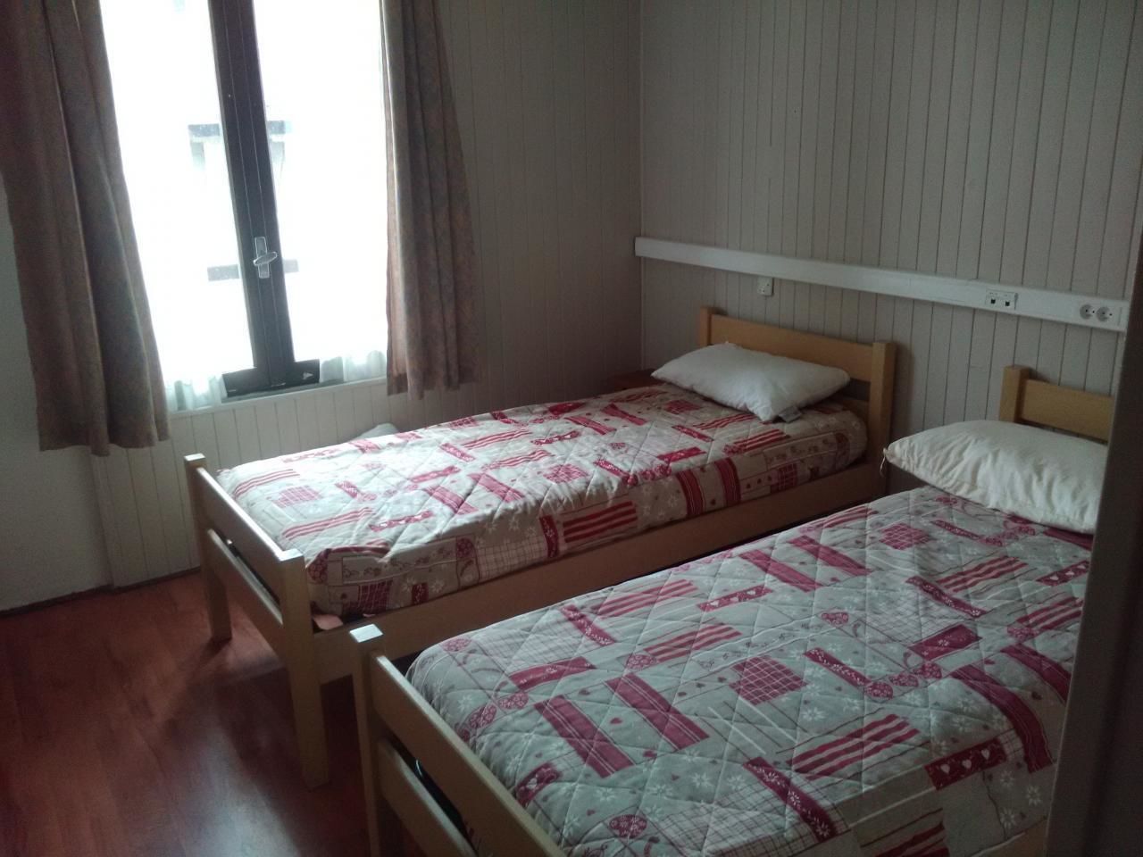 A room with two wooden beds, each with a quilted bedspread.