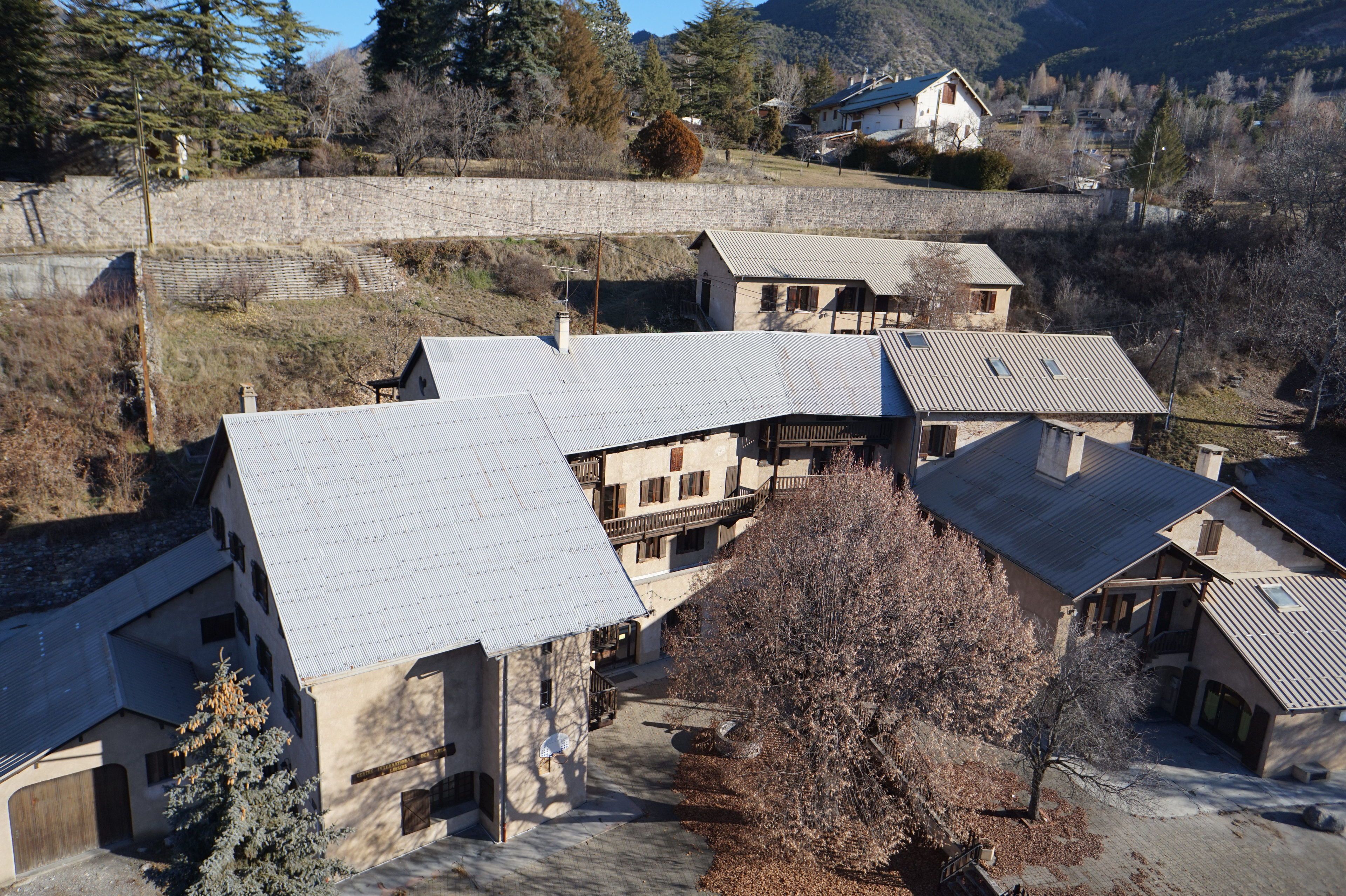 A residential area with multiple houses featuring sloped roofs and a stone wall in the background.