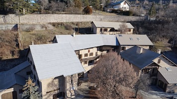 A residential area with multiple houses featuring sloped roofs and a stone wall in the background.