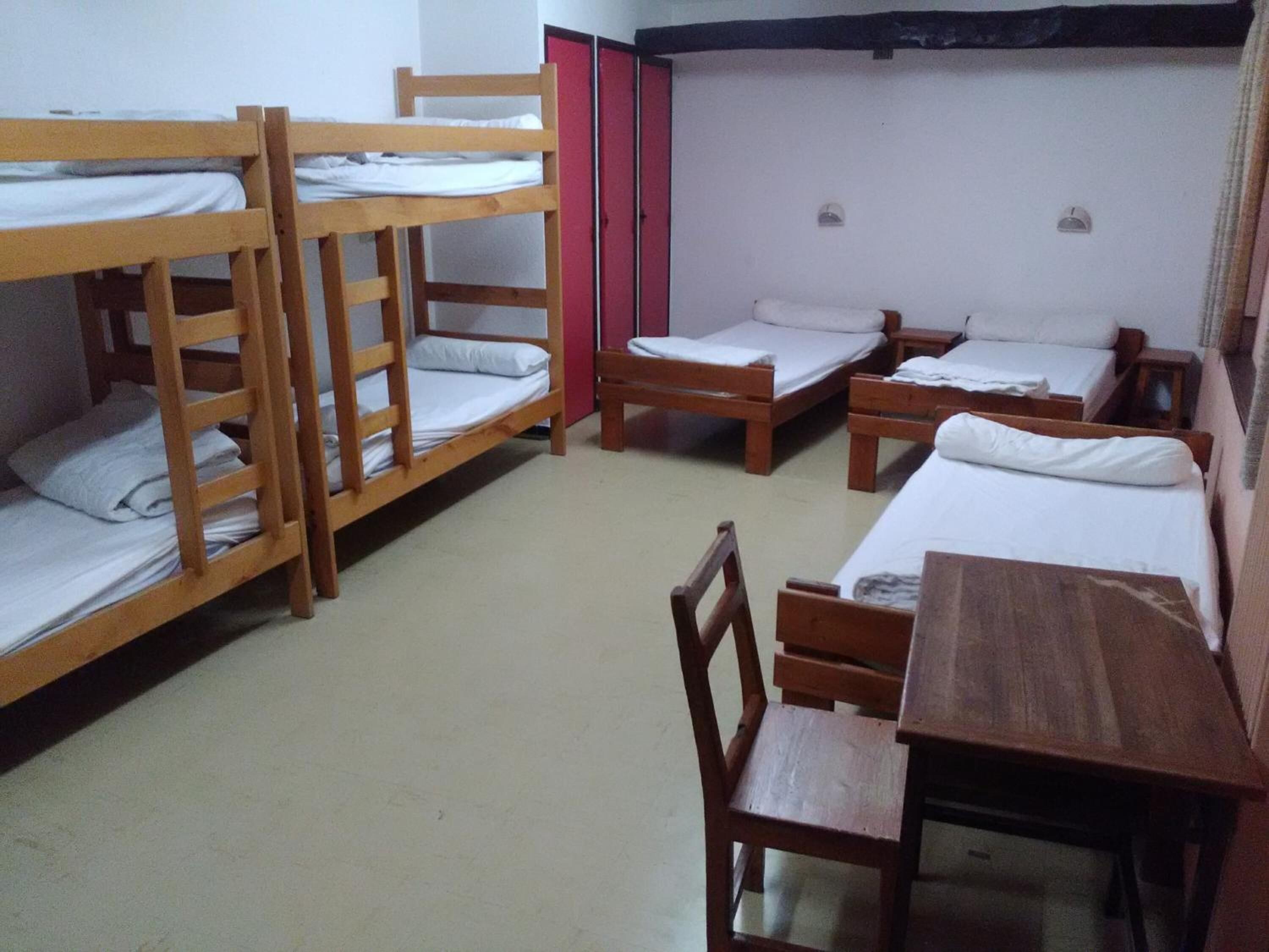 Un dormitorio con literas, un escritorio de madera y una silla.