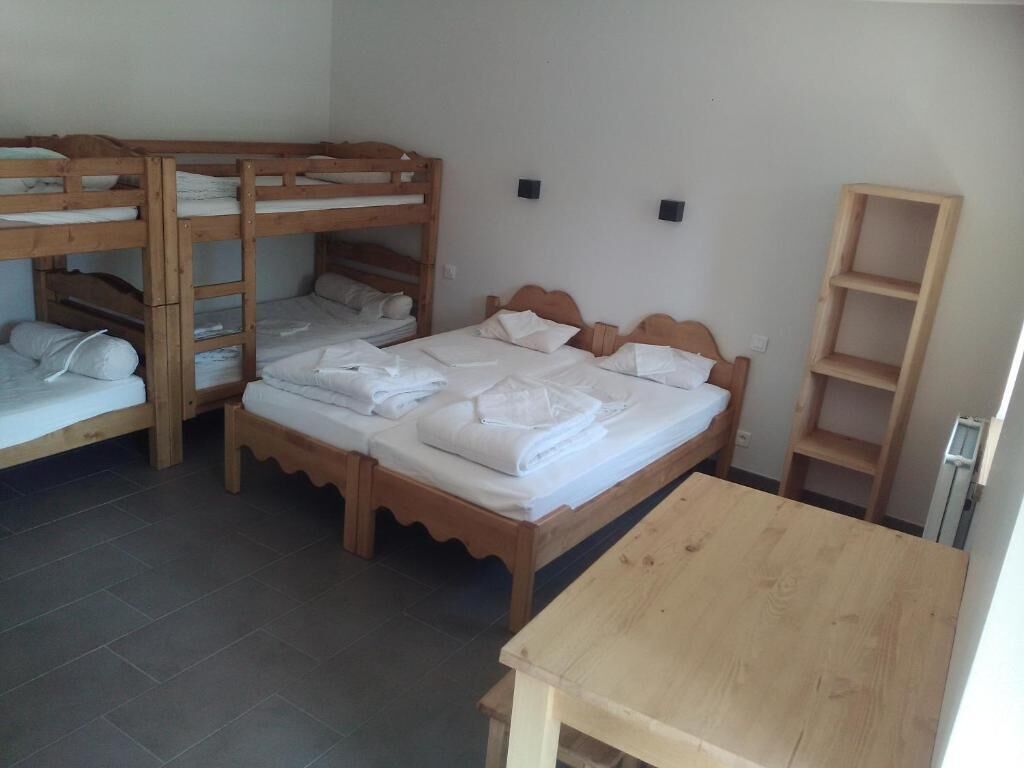 A room with bunk beds, a wooden table, and a shelf unit.