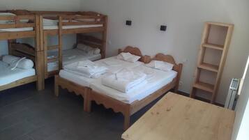 A room with bunk beds, a wooden table, and a shelf unit.