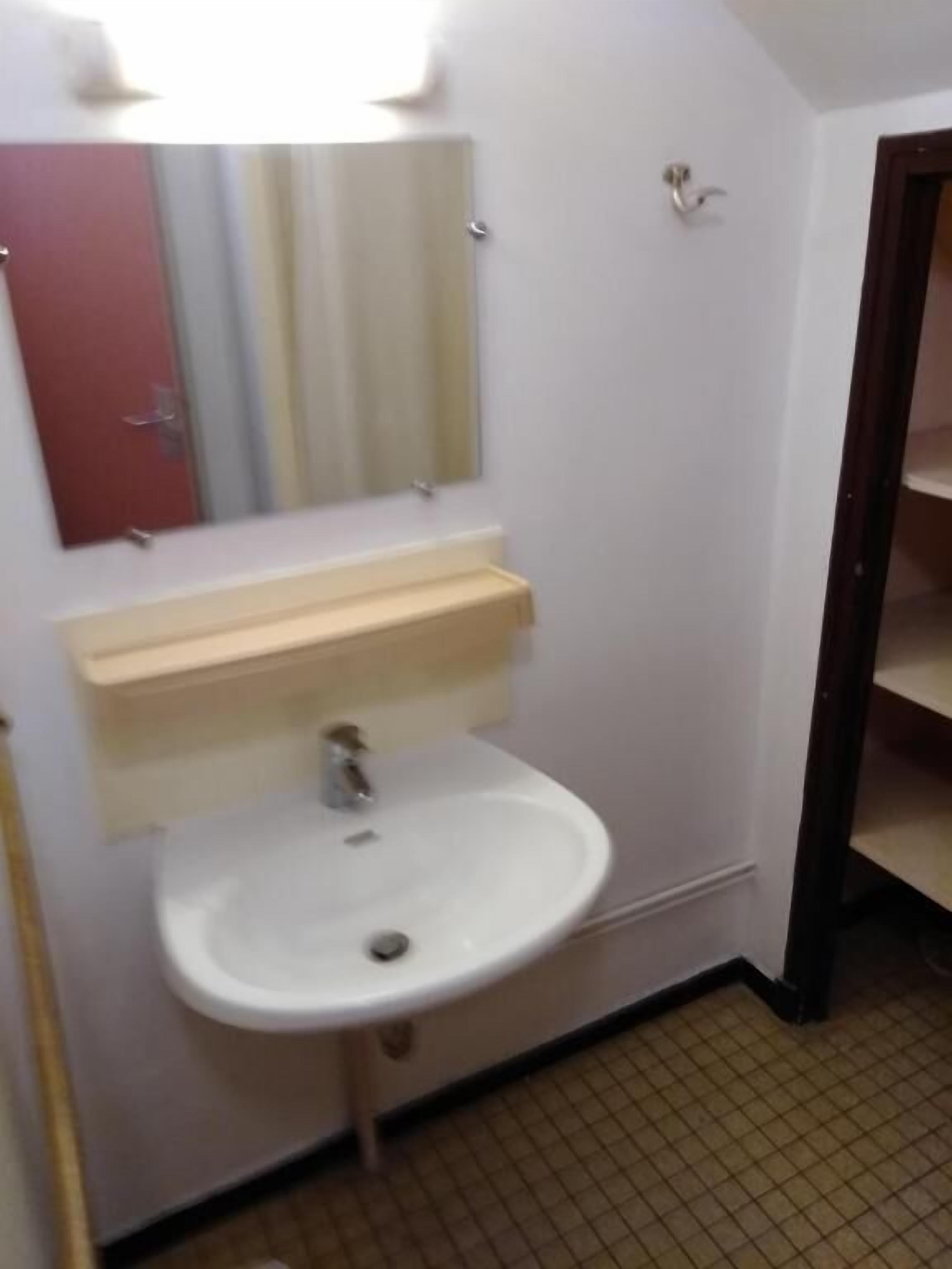 A bathroom with a white sink, a mirror, and a red door.