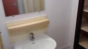A bathroom with a white sink, a mirror, and a red door.