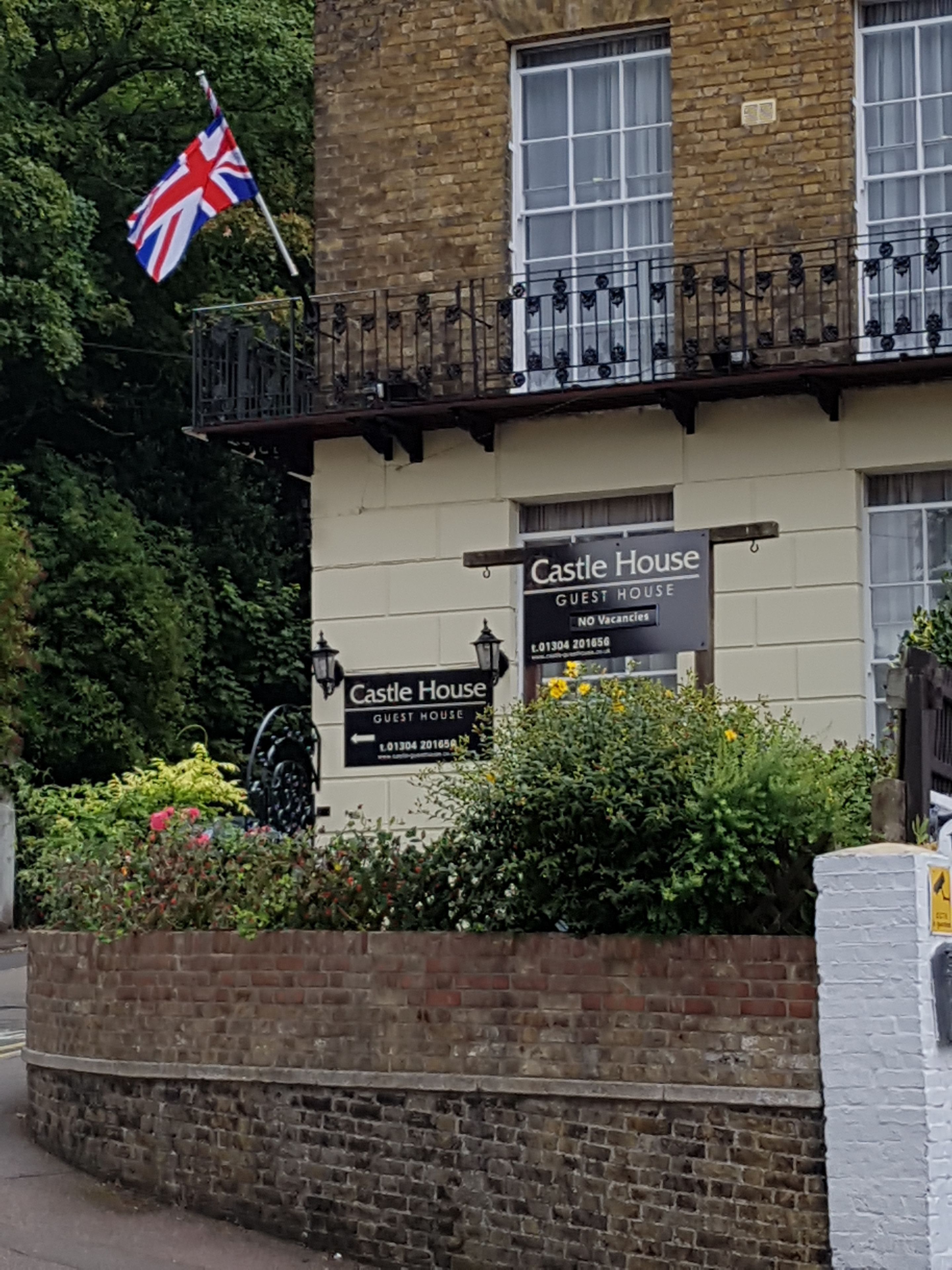 A building with a sign reading "Castle House Guest House" and a British flag.