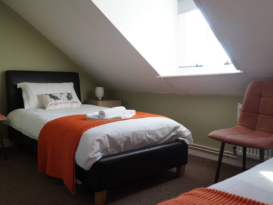 Une chambre à coucher avec un lit, une table de chevet, une chaise et une fenêtre.