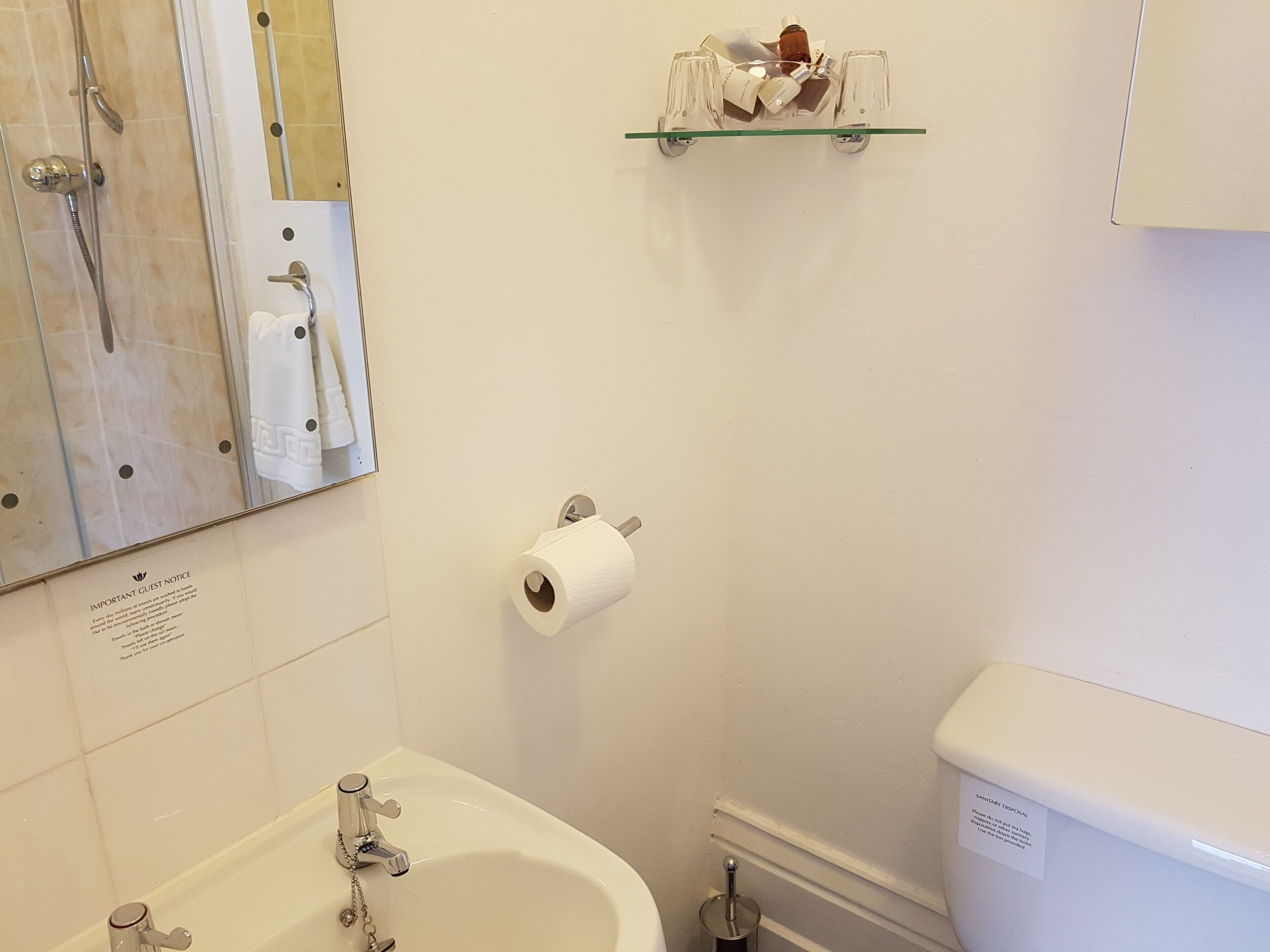 Une salle de bain avec une baignoire, des toilettes et une étagère en verre au-dessus des toilettes.