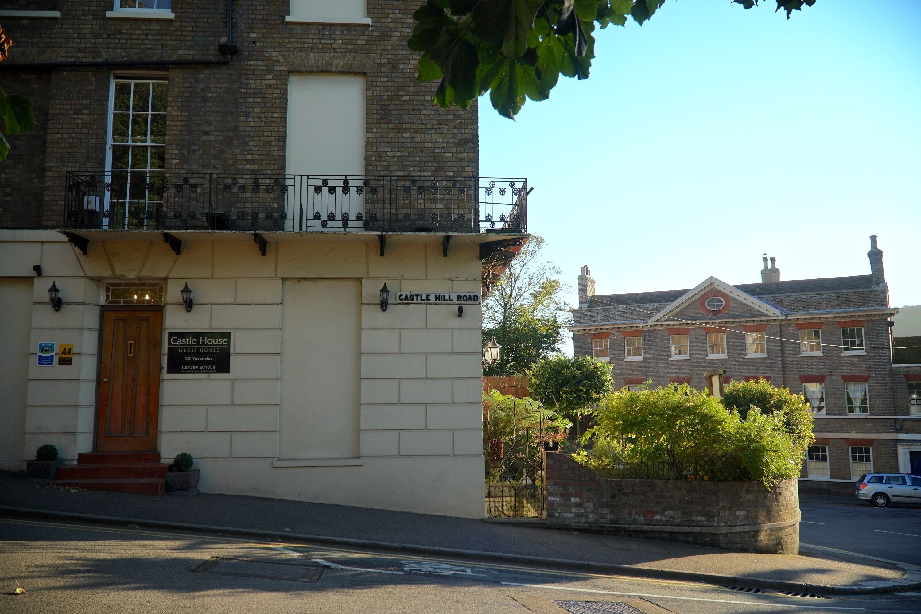 A building with a sign reading "Castle Hill Road" and "Castle House" indicating a guest house.