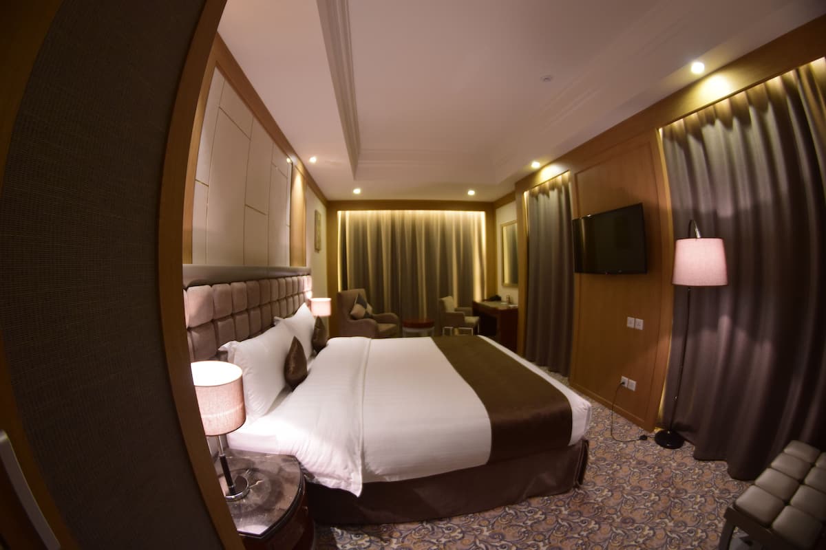 A hotel room with a large bed, a television, a desk, and a chair.