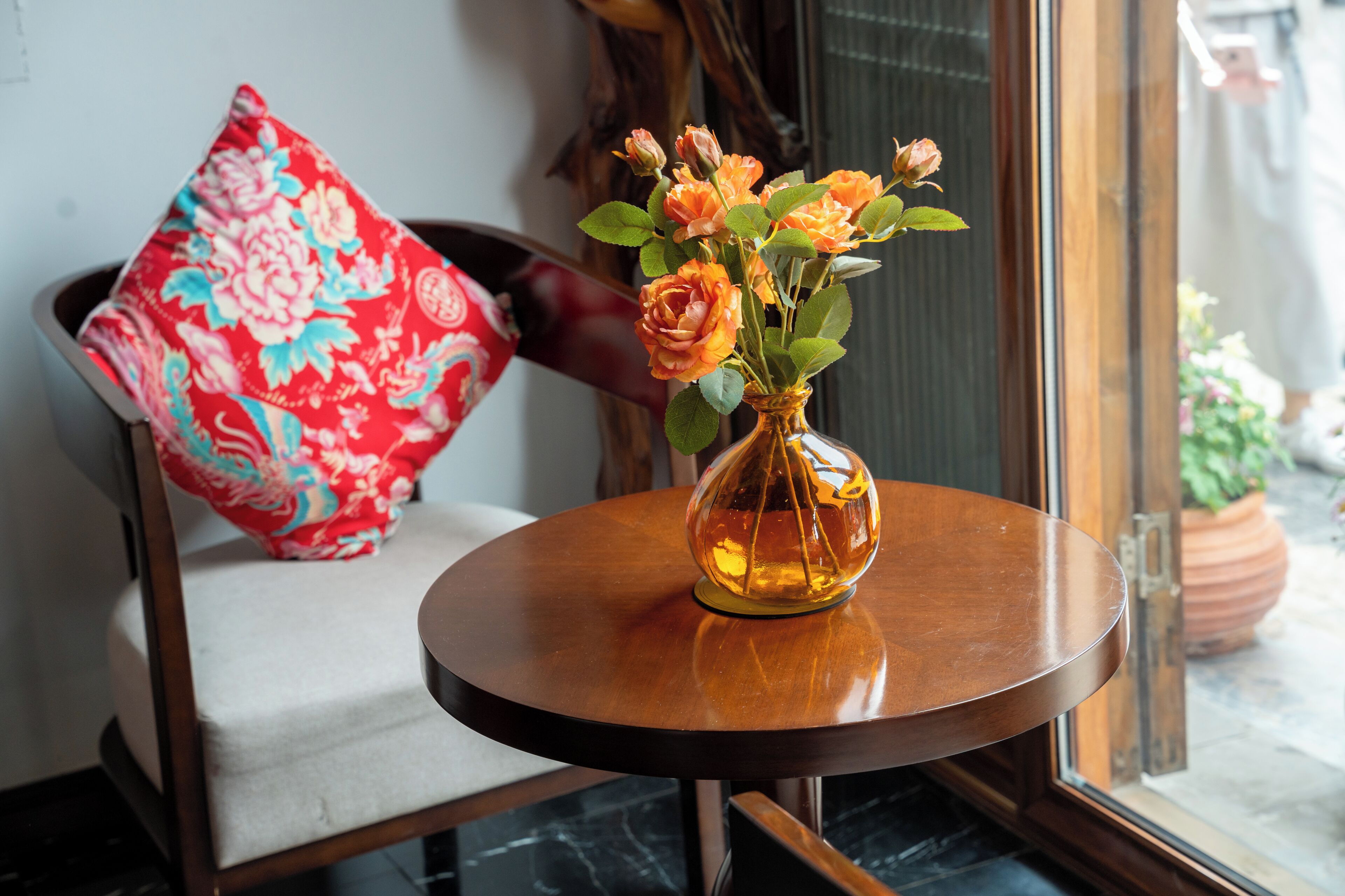 A round wooden table with a vase of flowers.