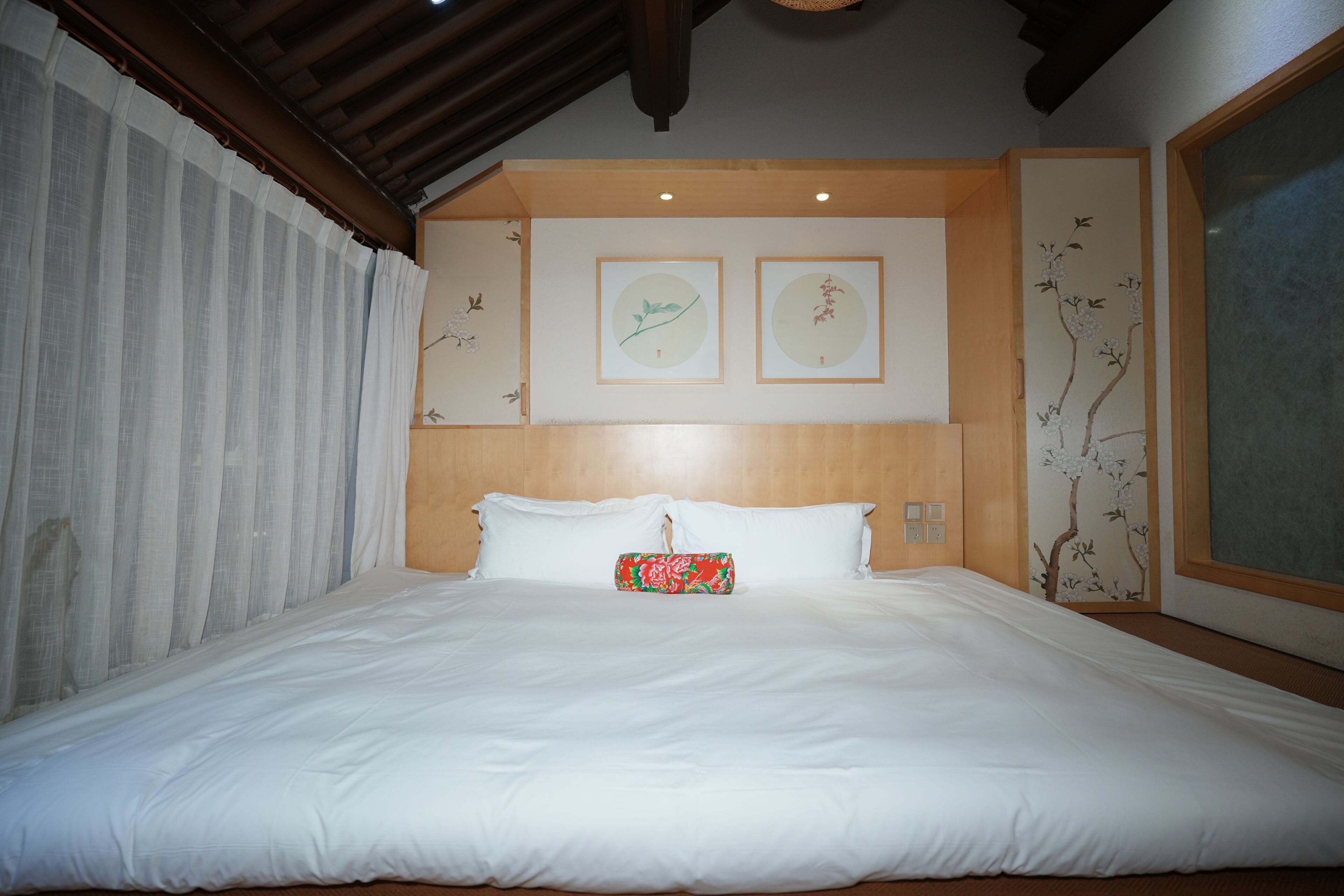 Una cama bien tendida con sábanas blancas, un almohadón y un objeto decorativo sobre la cama.
