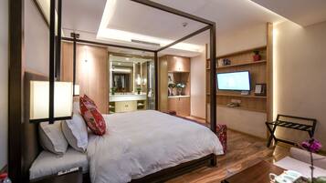 A modern hotel room with a large bed, a television, a desk, and a bathroom visible through an open door.