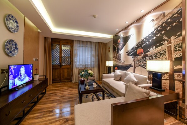 Una sala moderna con televisor, sofá, mesa de centro y elementos decorativos.