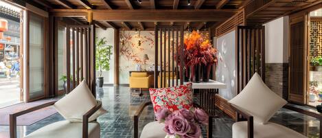 A lobby with two sofas, a vase with flowers, and a reception desk.