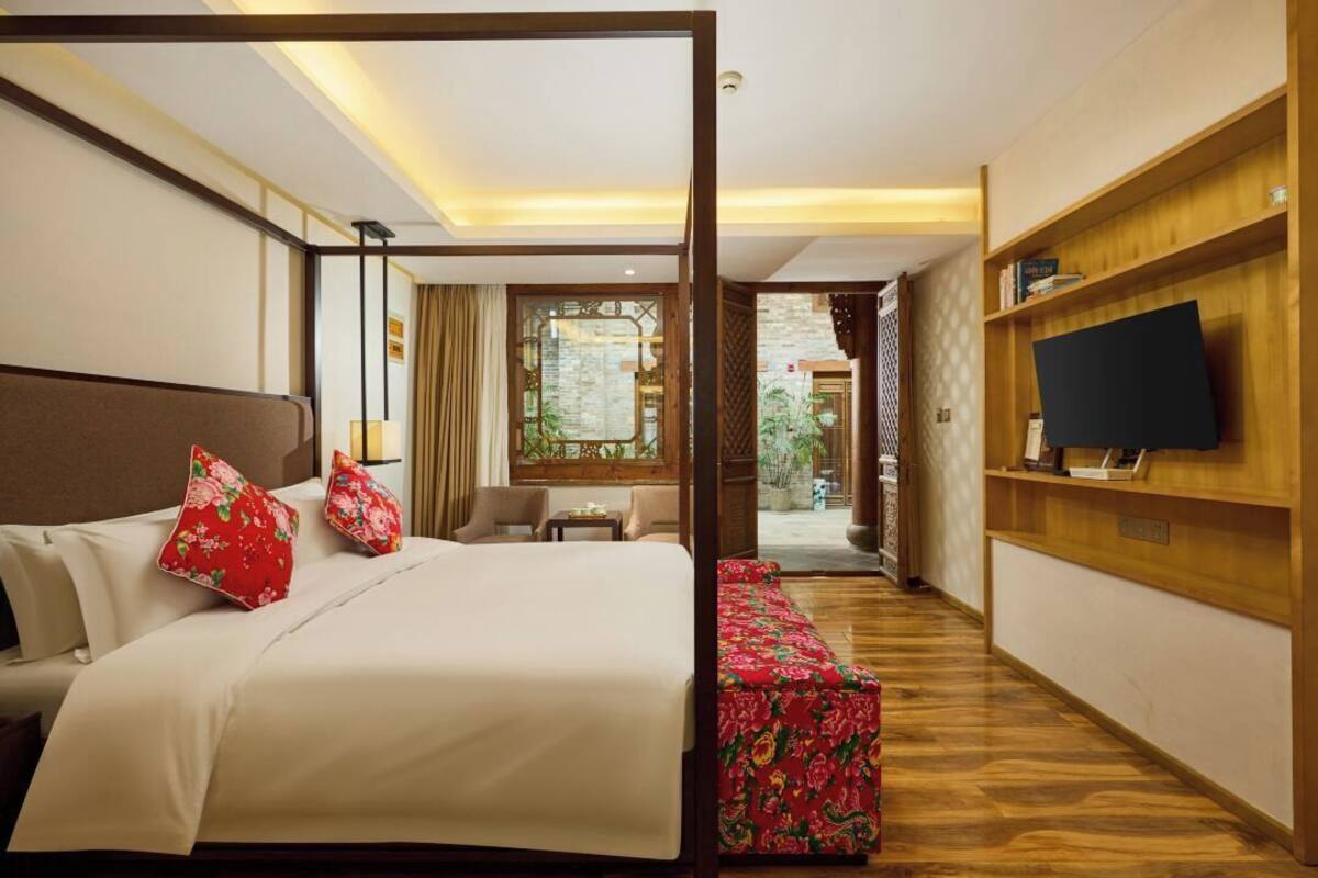 Habitación de hotel con cama, televisión, escritorio y vistas al exterior.