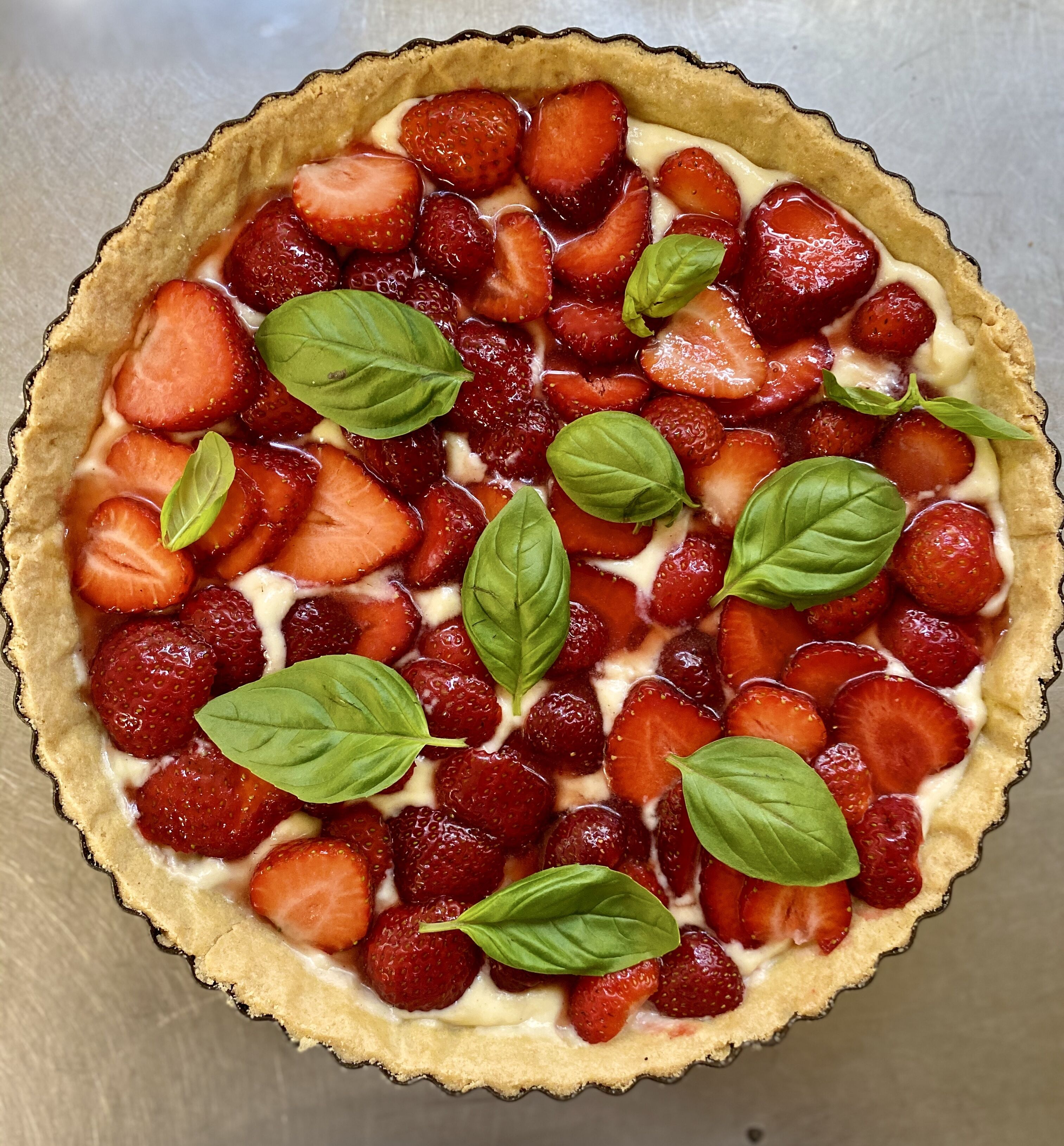 Una tarta de fresas con hojas de albahaca encima.