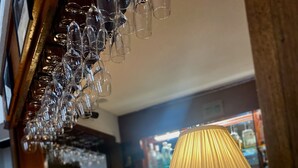 A bar area with a wooden counter, a lamp, and a vase with flowers. - THE Gordon Arms Restaurant With Rooms (Selkirk)