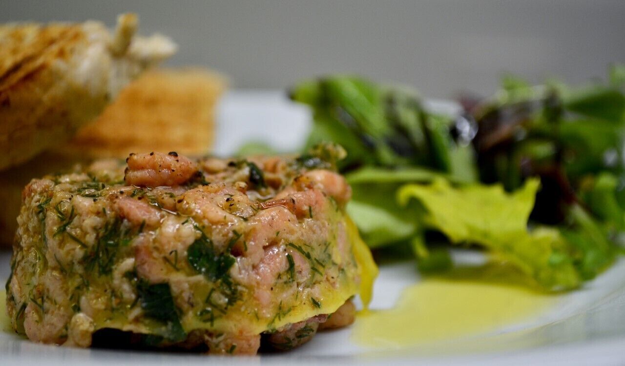 A plate with a meat-based dish, a side salad, and a piece of bread.
