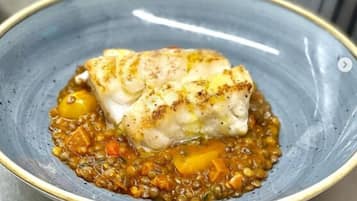 A plate with a piece of fish and lentil stew.