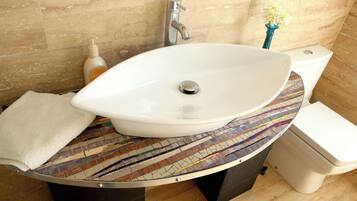 Un baño con un lavamanos de mosaicos, un inodoro blanco y una toalla en el suelo.