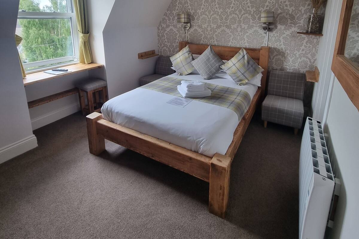 A bedroom with a wooden bed, a window with curtains, a radiator, and a patterned wall.