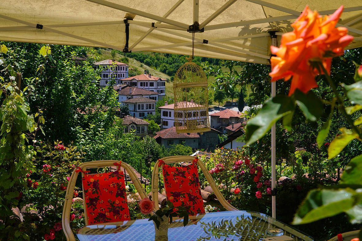 Un jardín con dos sillas de mimbre, una mesa y una jaula colgante para pájaros.